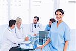 Portrait of a smiling female surgeon with colleagues in meeting at a medical office