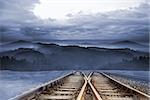 Train tracks leading to misty mountains