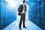 Smiling businessman with hands on hips against server hallway in the blue sky