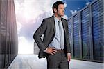 Businessman with hand on hip against server hallway in the sky