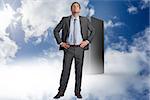Serious businessman with hands on hips against server tower in the blue sky