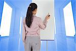 Businesswoman painting on an easel against bright blue room with windows