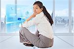 Businesswoman sitting cross legged smiling against abstract blue design in futuristic structure