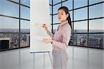 Businesswoman painting on an easel against room with large window showing city