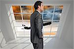 Smiling businessman with hand on hip against airplane flying over orange sky past window