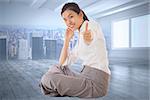 Businesswoman sitting cross legged showing thumb up against city scene in a room