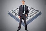 Happy businessman with hand in pocket against maze puzzle