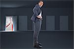 Happy businessman with hands on hips against door opening to show red arrow and sky