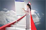 Businesswoman painting on an easel against cloudy sky background