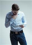 Young man looking down at tablet computer, studio shot on white background