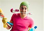 Close-up portrait of young man goofing around and holding colorful cleaning supplies, studio shot on white background