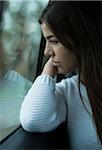 Portrait of young woman sitting inside car and looking out of window and day dreaming on overcast day, Germany