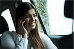 Young woman sitting inside car and talking on cell phone, on overcast day, Germany