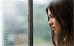 Close-up portrait of young woman day dreaming and looking out window, Germany