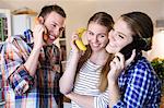 Three young people having fun using fruit as telephones
