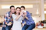 Three young people having fun taking photographs in the kitchen