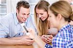 Three young people looking at cell phones and smiling