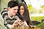 Young couple in tent using smartphone