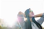 Young woman with hands behind head in sunlight