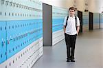 Portrait of schoolboy with hands in pockets in school corridor