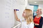 Schoolgirl doing multiplication on white board