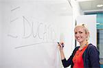 Portrait of female writing on white board