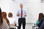 Mature male teacher in front of class