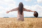 Mid adult woman standing in wheat field with arms out wide