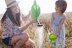 Mother and daughter in wheat field with watering cans