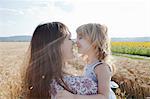 Mother and daughter in wheat field hugging