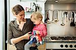 Mother carrying baby girl in kitchen