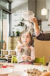 Mother and daughter sieving flour in kitchen