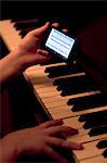 Close up of hands using smartphone whilst playing piano
