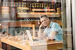 Businessman using laptop, view through window