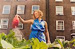 Young woman watering vegetables on council estate allotment