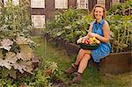 Young woman with harvested vegetables on council estate allotment