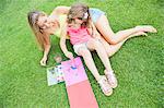 Mother and daughter painting, sitting on grass