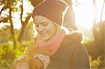 Portrait of young woman in park, holding autumn leaf