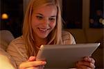 Young woman sitting on sofa, using digital tablet