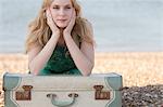 Portrait of young woman with suitcase on beach, Whitstable, Kent, UK