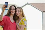 Two young female friends taking self portrait, Whitstable, Kent, UK