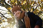 Smiling young woman wrapped up in autumnal park