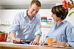 Adult grandson and grandmother looking at digital tablet