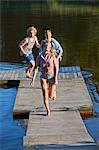 Three young adult friends running on pier, Gavle, Sweden