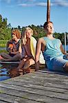 Three young adult friends relaxing on pier, Gavle, Sweden