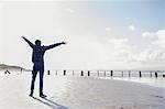 Young man standing on beach with arms out, Brean Sands, Somerset, England