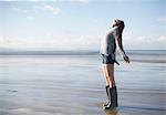 Young woman standing on beach looking up, Brean Sands, Somerset, England