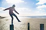 Young man standing on groynes, Brean Sands, Somerset, England