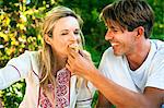 Young man feeding girlfriend on the riverside, foothills of the Alps, Bavaria, Germany