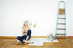 Woman sits on parquet floor using phone, Munich, Bavaria, Germany